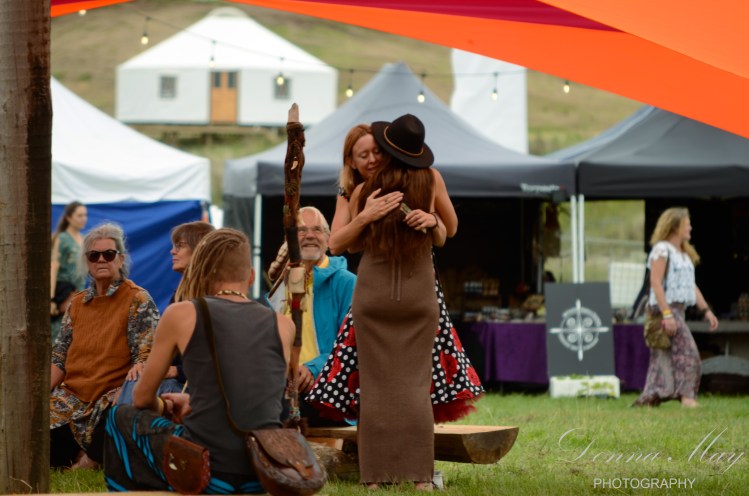A photograph of two woman hugging at a festival