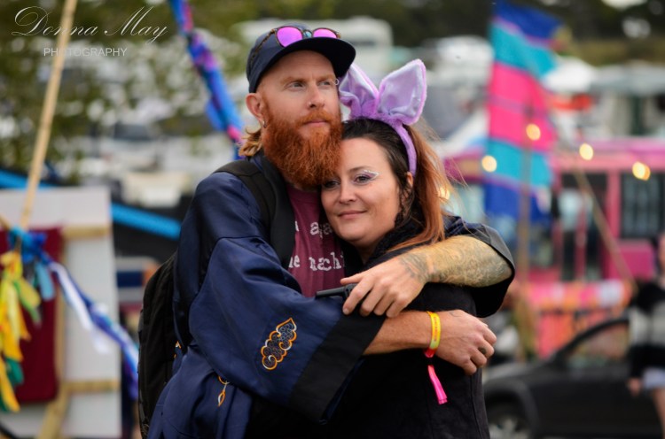Photograph of a young couple cuddling at a festival