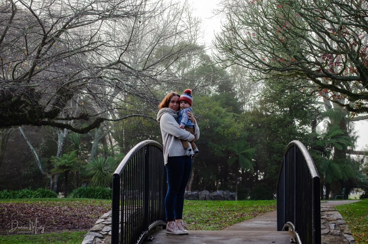 A photograph of a mum and her baby standing on a bridge at a park
