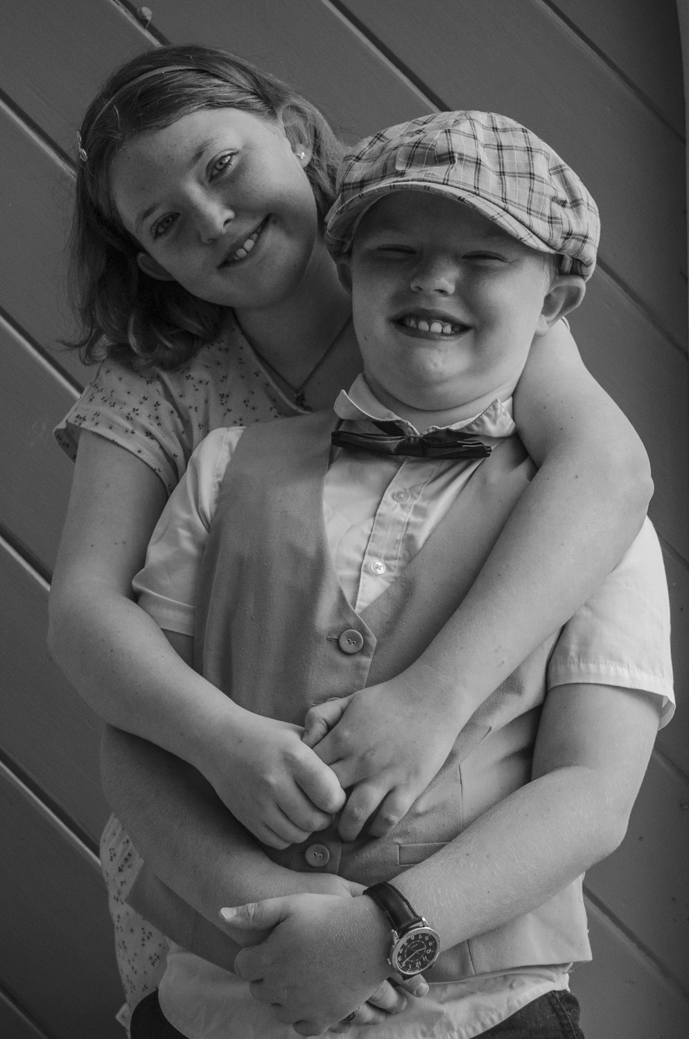 A black and white family portrait photograph of a sister cuddling her little brother. Taken by Te Awamutu, Waikato based photographer, Donna from Donna May Photography.