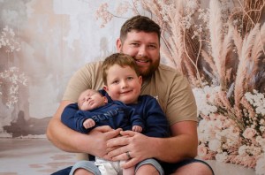 A family portrait photo of a father cradling his young son who's cradling his newborn brother. Taken by Te Awamutu, Waikato based photographer, Donna from Donna May Photographer.