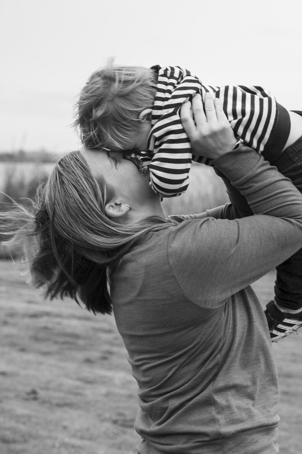 A black and white portrait photo of a mum lifting her young son in the air. Taken by Te Awamutu, Waikato based photographer, Donna form Donna May Photography
