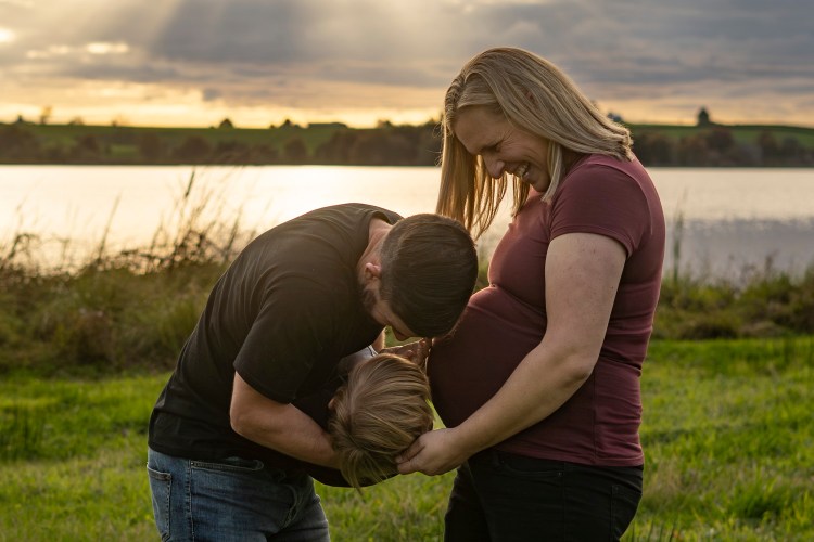 A family maternity photograph of an expectant mum, her husband and young son.