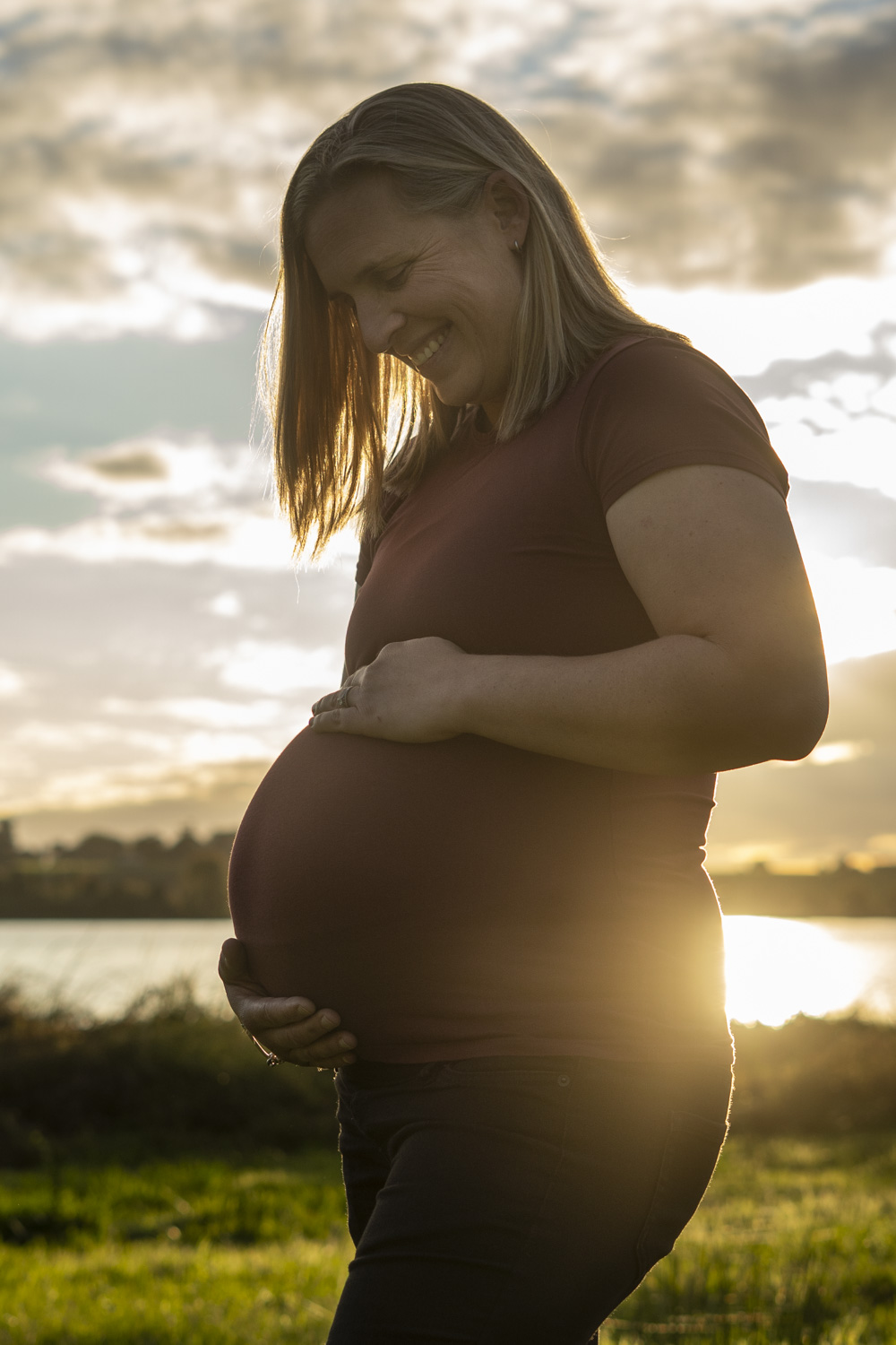 A maternity photo taken of an expectant mum next to a lake in Te Awamutu. Photo taken at golden hour by Donna from Donna May Photography. A Waikato, Te Awamutu based lifestyle family photographer.