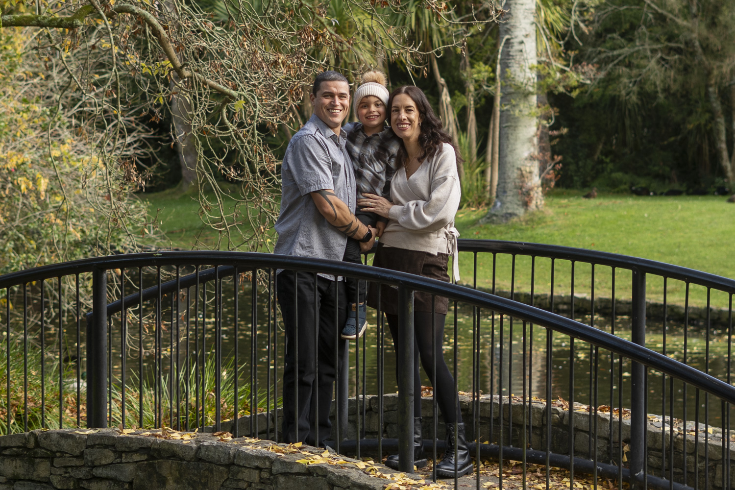 A portrait photo of a young family stood on a bridge in Te Awamutu War Memorial Park. Taken by Te Awamutu, Waikato based photographer, Donna from Donna May Photography.