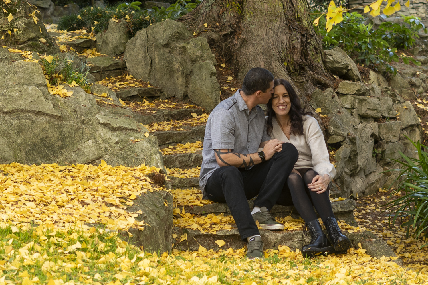 A portrait photo of a couple sharing an intimate moment whilst sat on park steps in autumn. Taken by Te Awamutu, Waikato based photographer, Donna from Donna May Photography