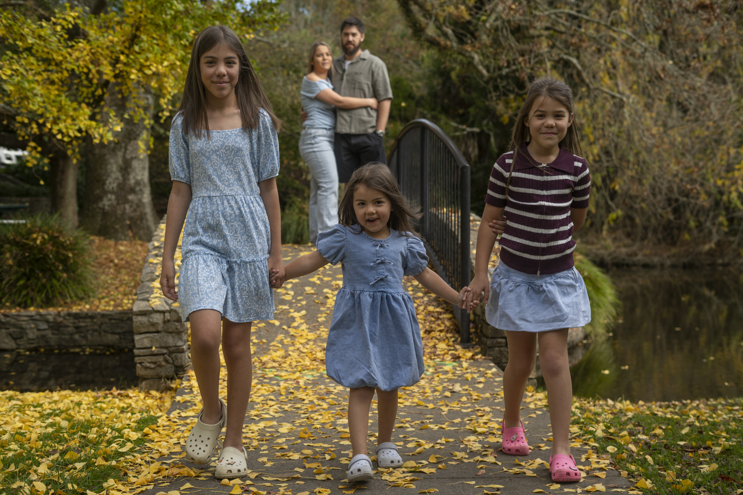 A lifestyle portrait photo of three young sisters walking and holding hands. Taken in autumn by Te Awamutu, Waikato based photographer, Donna from Donna May Photography
